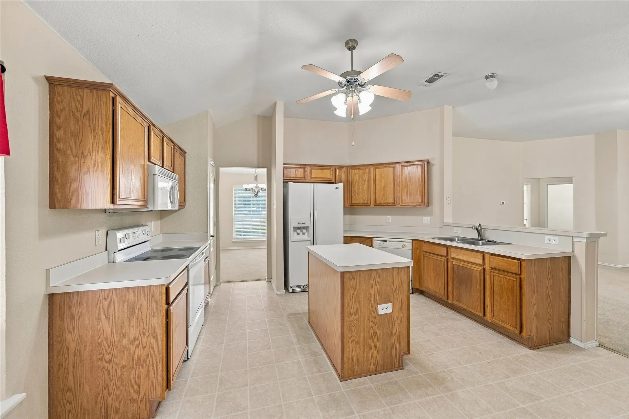 Kitchen featuring wood cabinetry, laminate countertops, a center island, vaulted ceilings, and tile flooring