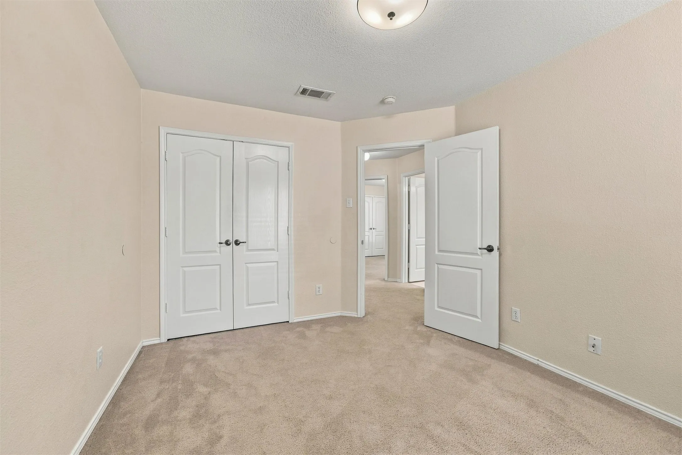 Room featuring neutral-toned carpeting, double-panel interior doors, and a central flush-mount ceiling light fixture