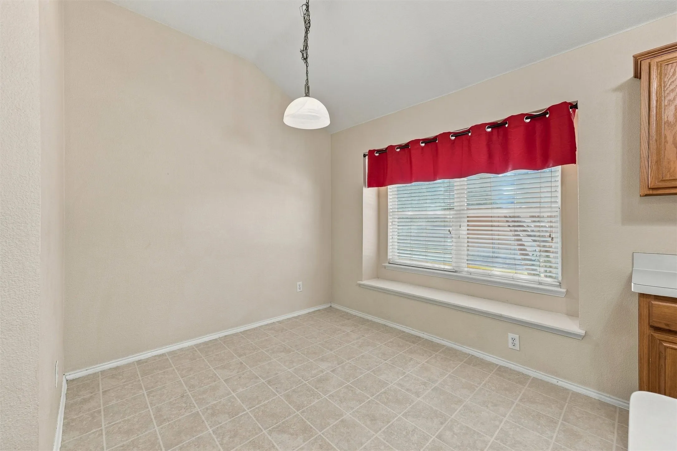 Tile flooring, built-in window bench seating, oversized window with horizontal blinds, and a suspended dome pendant light fixture