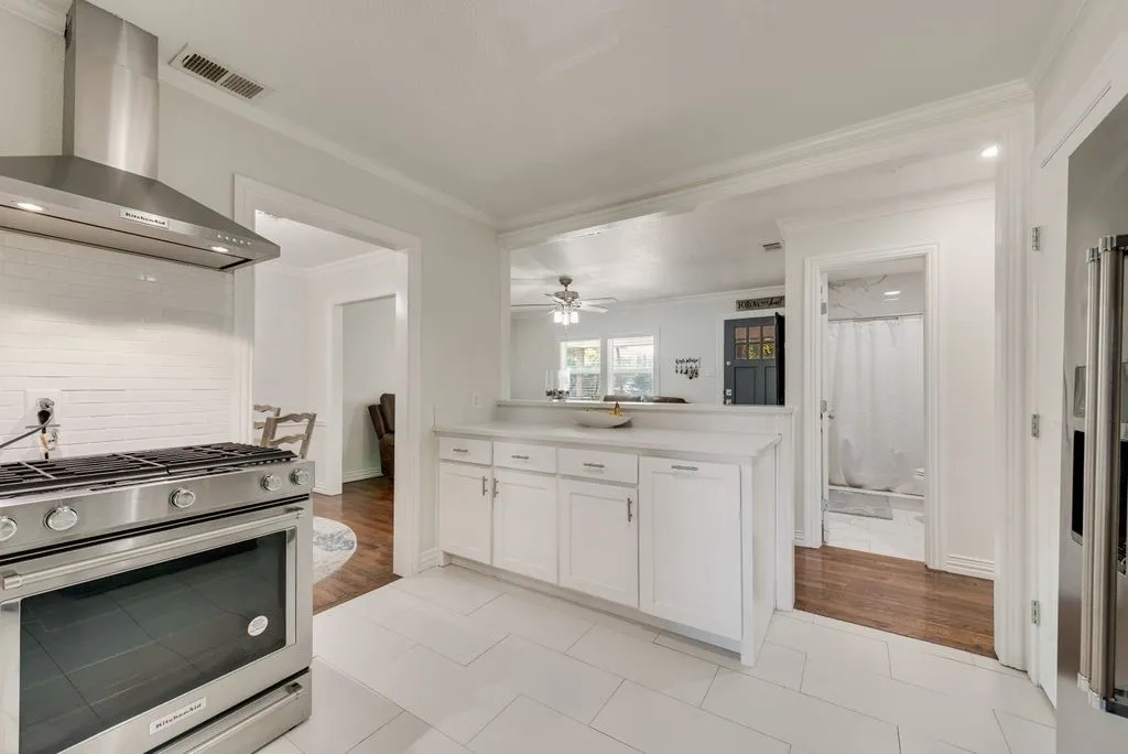 Kitchen featuring white shaker cabinetry, stone-finish countertops, stainless steel range with a professional-style chimney hood, and large-format tile​​‌​​​​‌​​‌‌​‌‌​​​‌‌​‌​‌​‌​​​‌​​ flooring