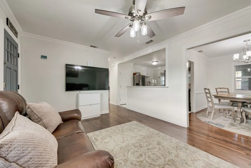 Wood-finish flooring, crown molding, and a multi-light ceiling fan