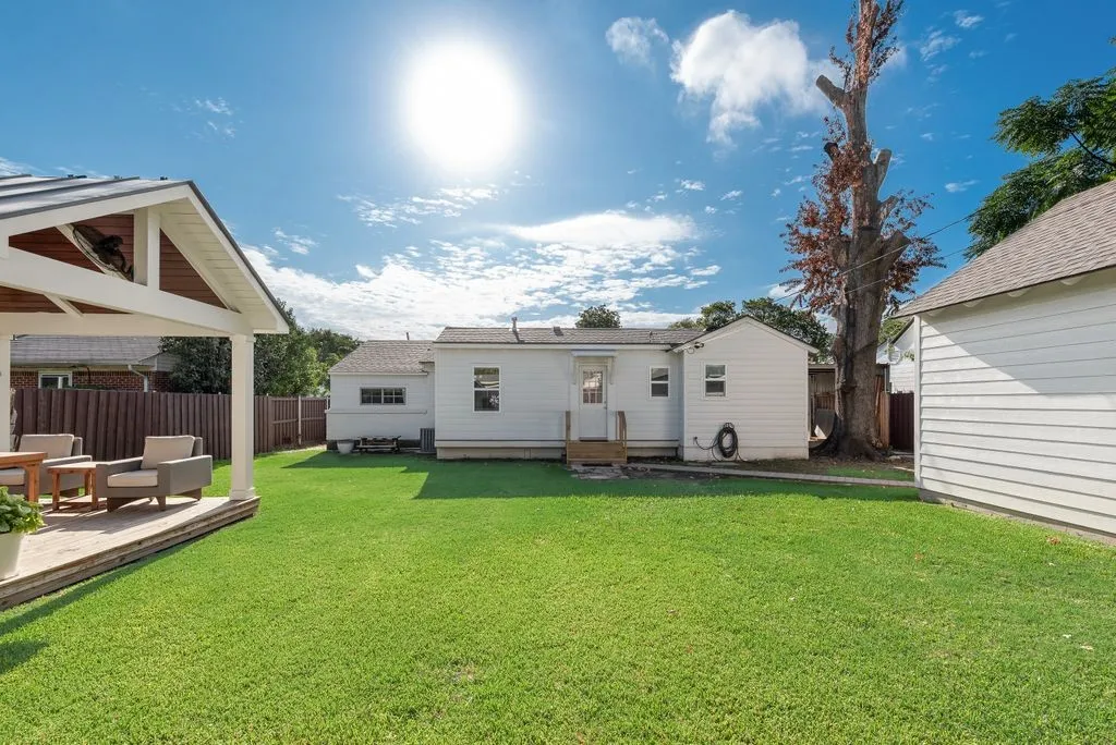 Backyard featuring a manicured lawn, a covered patio with a gable roof, wood-finish decking, and privacy fencing