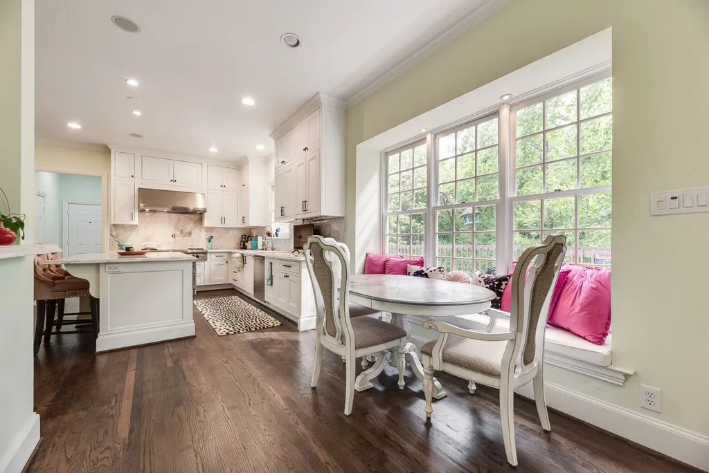 Kitchen featuring white shaker-style cabinetry, a large center island, wood-finish flooring, recessed lighting, and a window-lined breakfast nook with a built-in bench