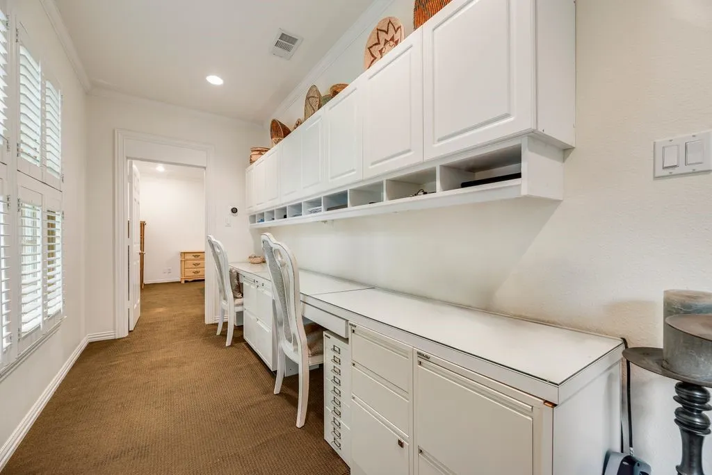 Built-in white cabinetry featuring upper storage units, open shelving, and integrated desk workspace with drawers