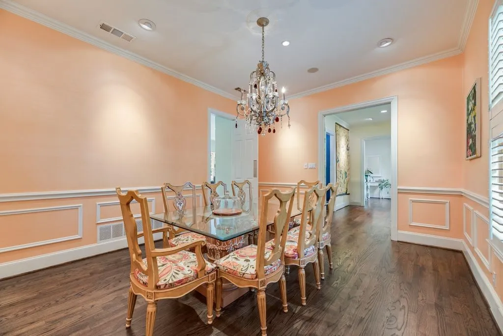 Dining area featuring wood-finish flooring, decorative wall molding, crown molding, and an ornate crystal chandelier