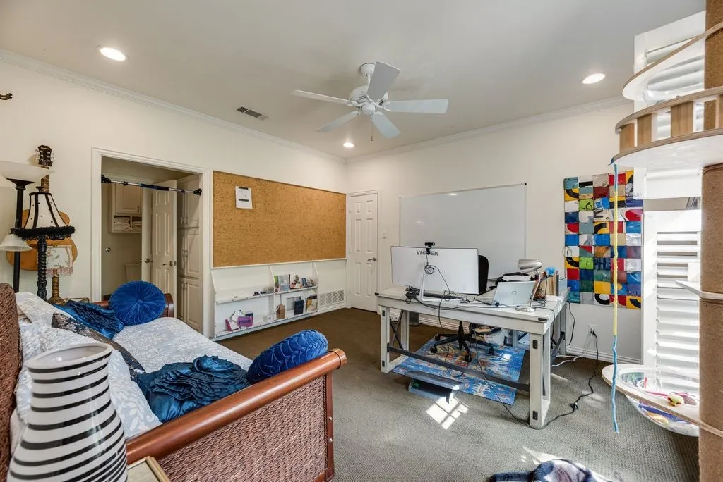 Neutral-toned interior space featuring recessed lighting, a white ceiling fan, wall-to-wall carpeting, and a built-in wall-mounted cork board with integrated shelving
