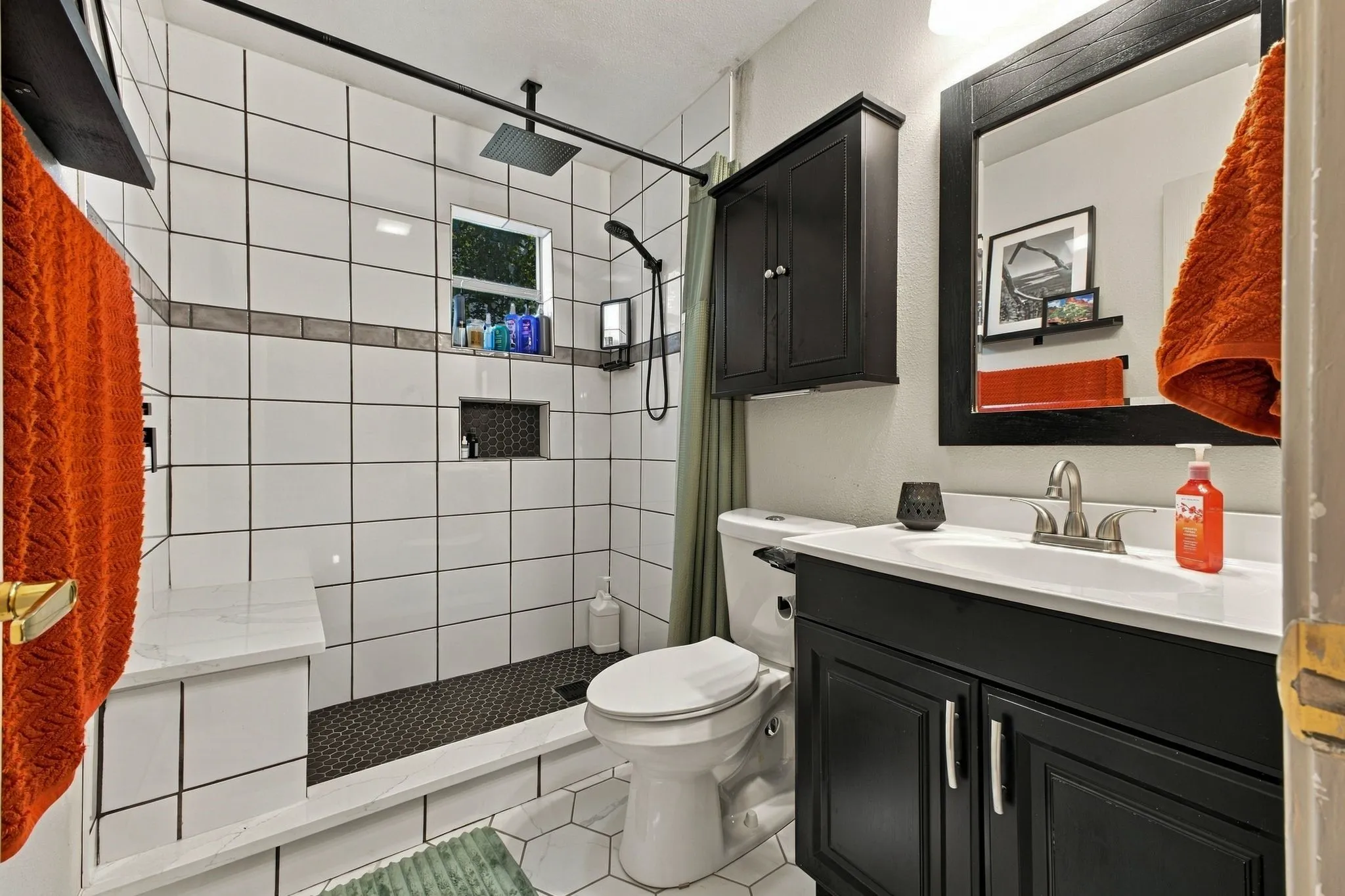 Bathroom featuring a vanity with a white countertop, dark cabinetry, and a matching framed mirror
