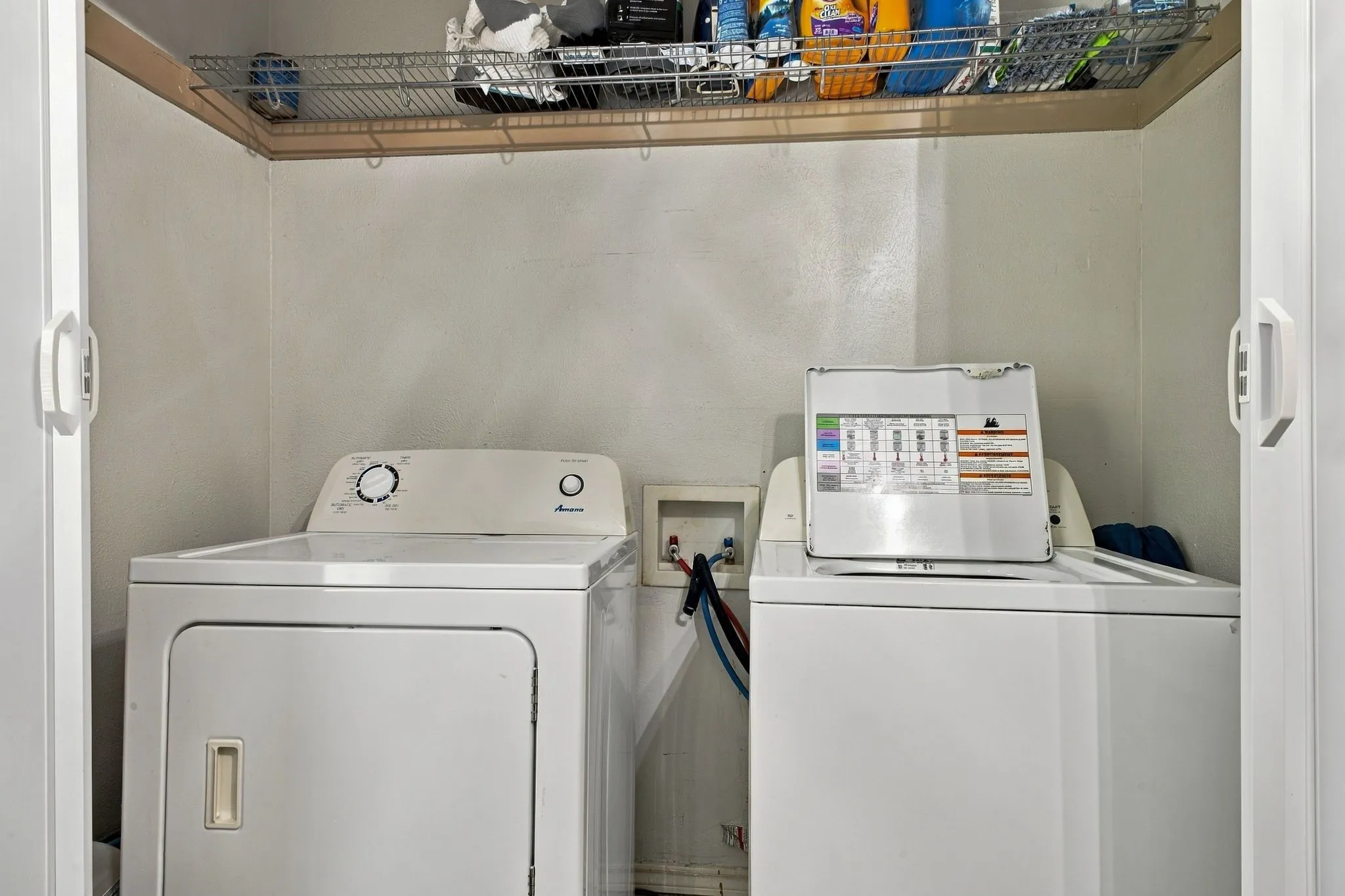 Laundry closet featuring sliding white doors, wire shelving, and dedicated plumbing hookups