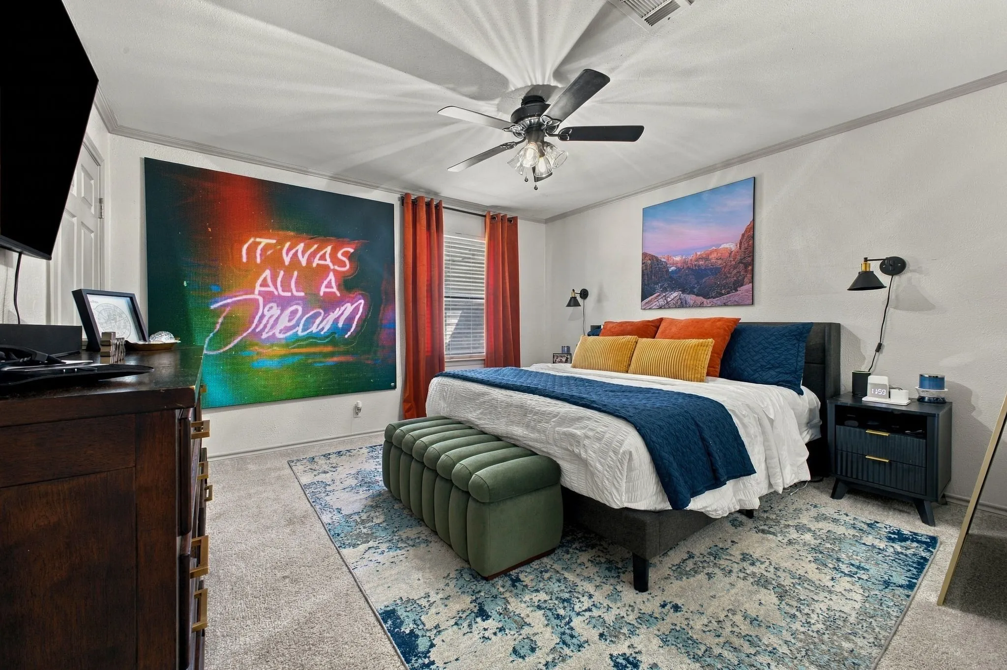 Bedroom featuring neutral wall-to-wall carpeting, crown molding, a central ceiling fan with integrated lighting, and two wall-mounted adjustable sconces