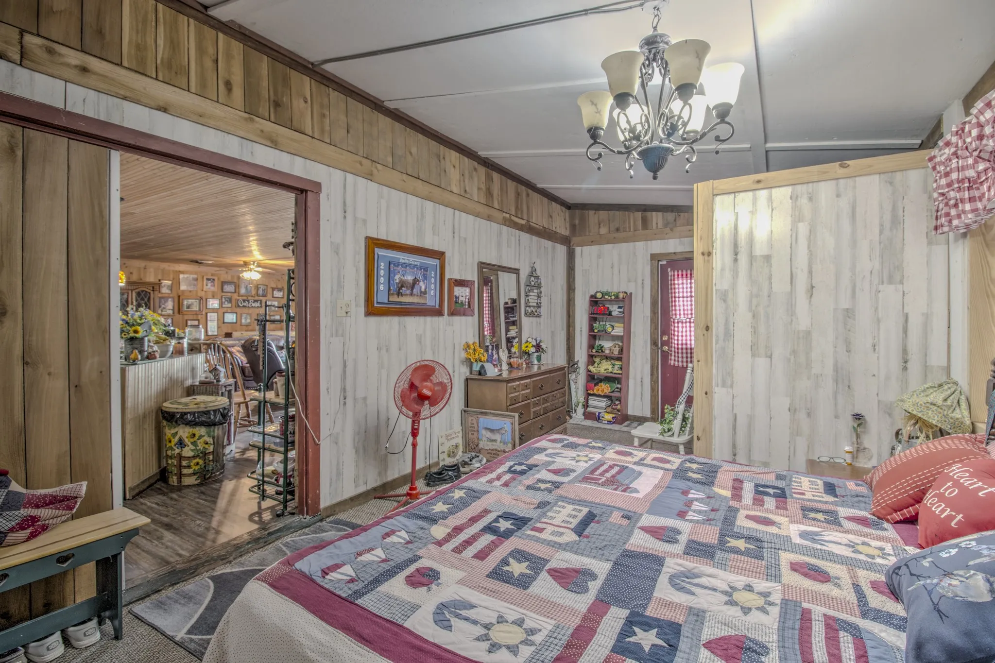 Vertical wood-plank wall paneling, multi-toned decorative wood trim, and a multi-arm candelabra-style chandelier