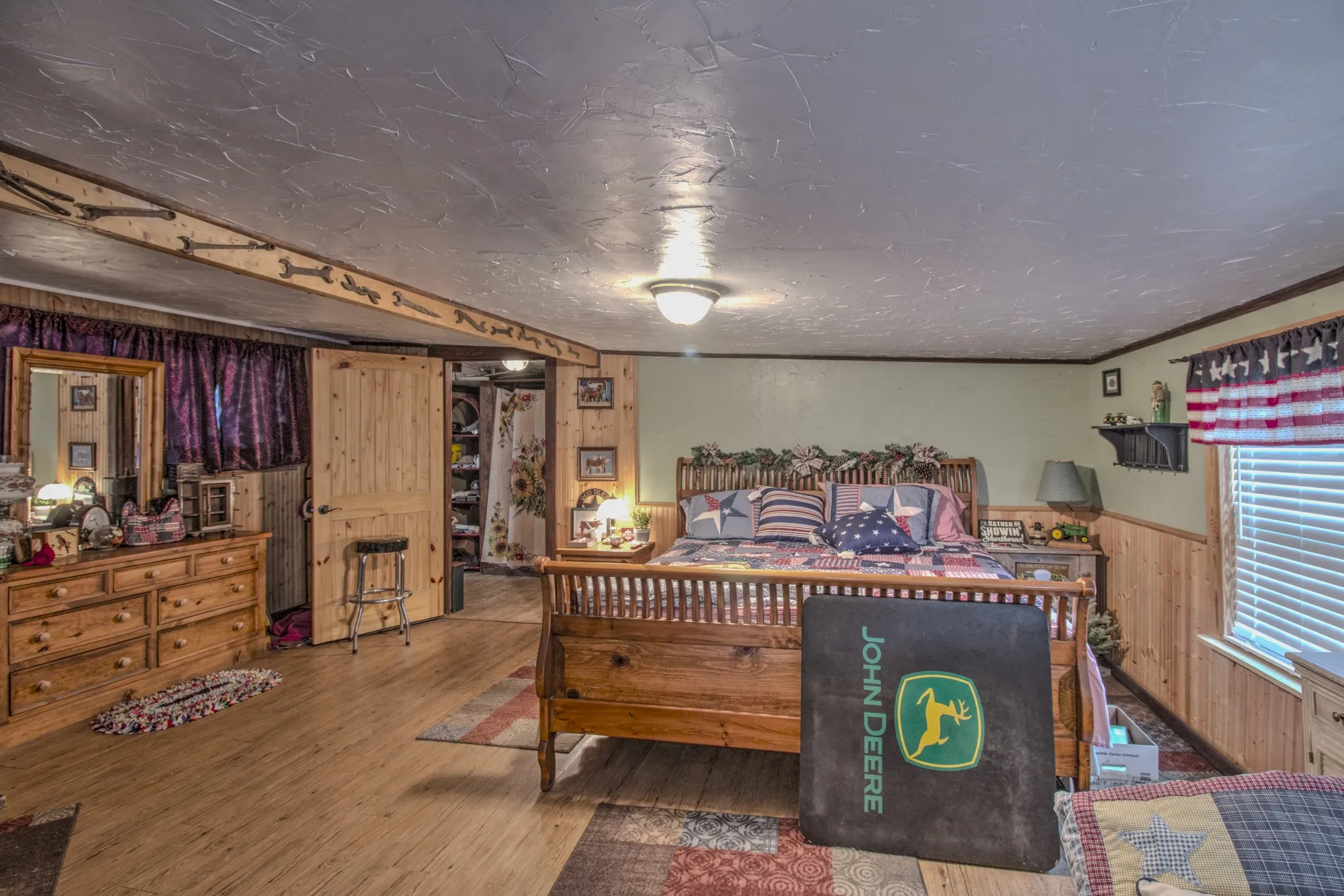 Room featuring wood-finish flooring, half-wall wood paneling, a textured ceiling, and a decorative exposed ceiling beam