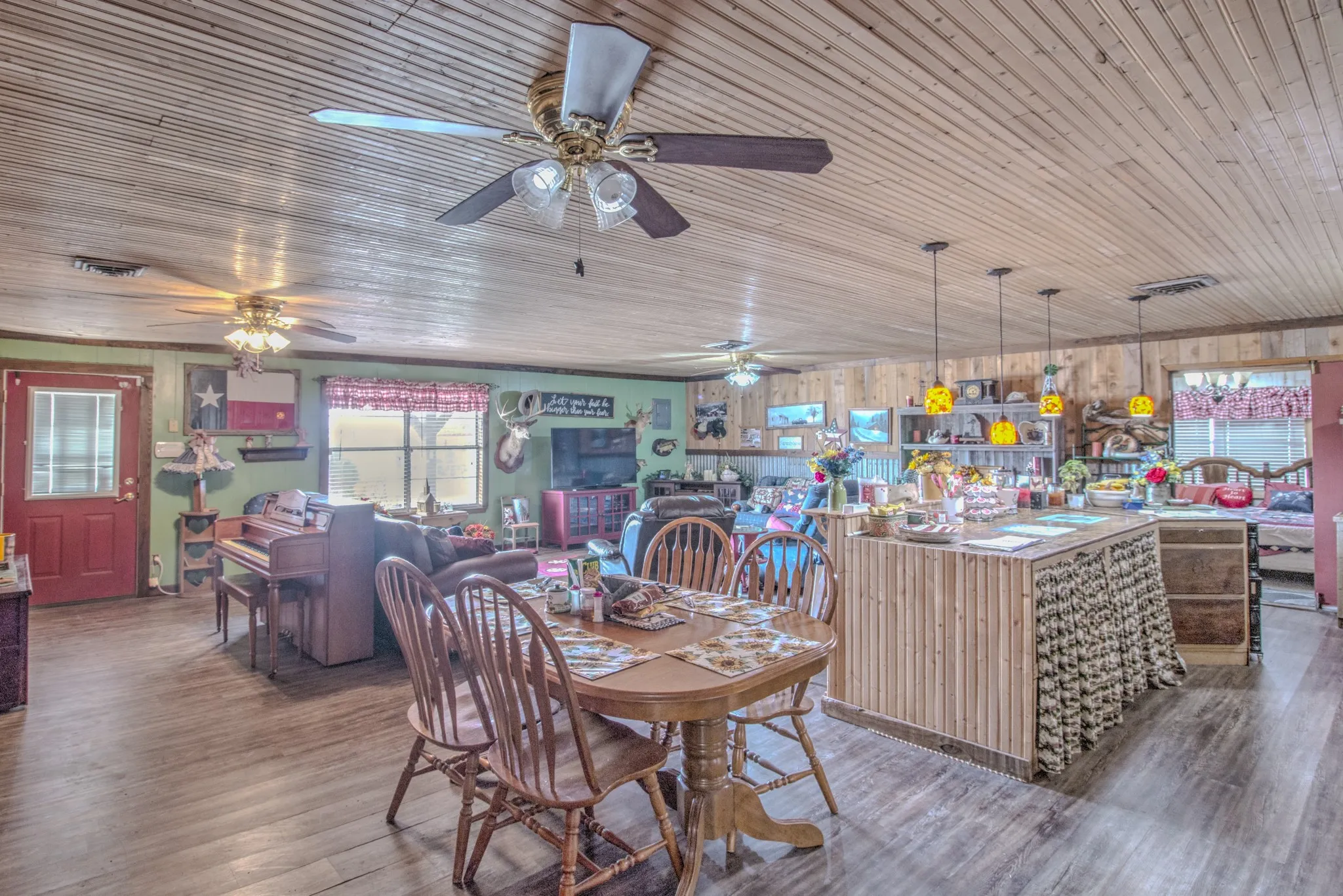 Wood-plank ceiling, wood-finish flooring, central island with wood-slat cabinetry, and multiple ceiling fans