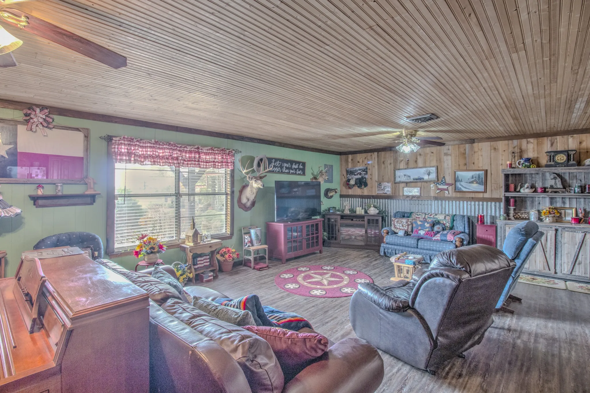 Beadboard wood ceiling, wood-paneled walls, corrugated metal wainscoting, and large picture window