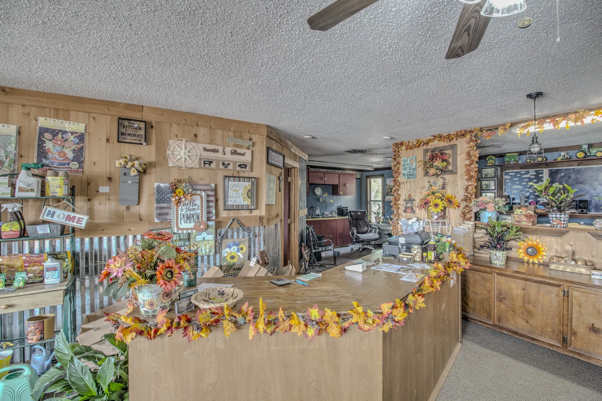 Interior space featuring natural wood wall paneling, corrugated metal accent wainscoting, a custom built-in service counter, and overhead pendant and ceiling fan lighting