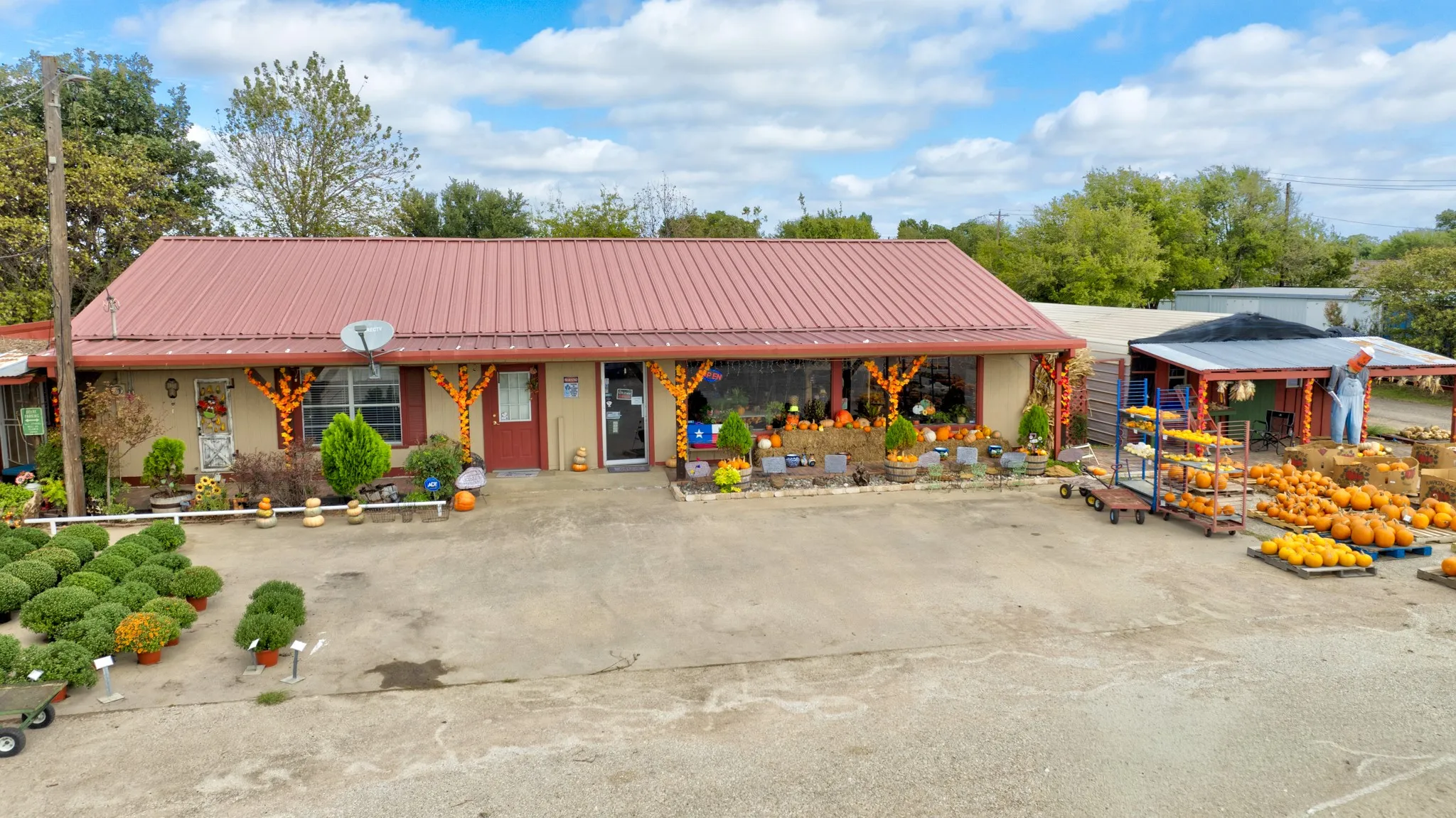 Single-story structure featuring a metal roof, expansive concrete exterior lot, covered porch, and glass storefront window panels