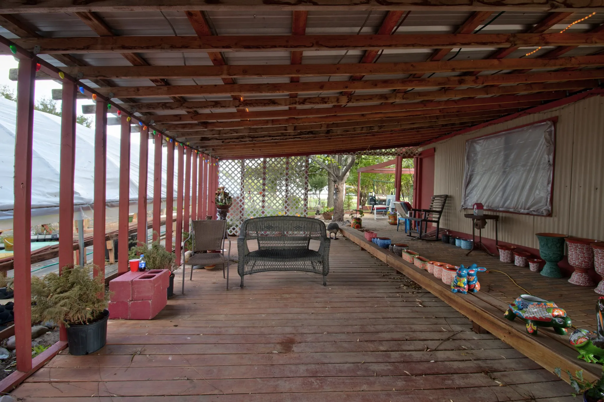 Covered wood deck featuring an exposed rafter ceiling, lattice privacy screening, and vertical support posts