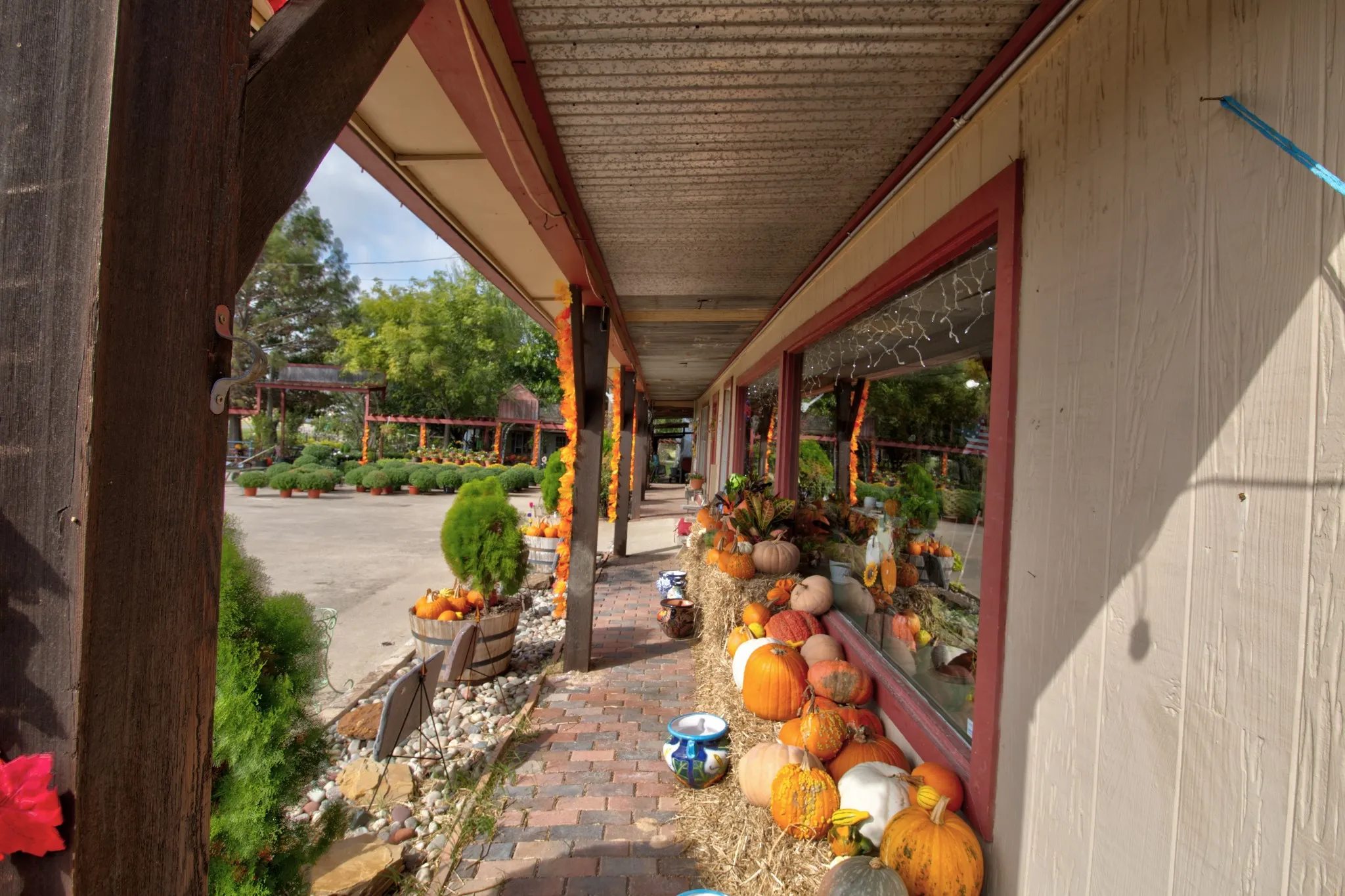 Covered exterior walkway featuring brick pavers, wood structural posts, and large display windows with wood trim