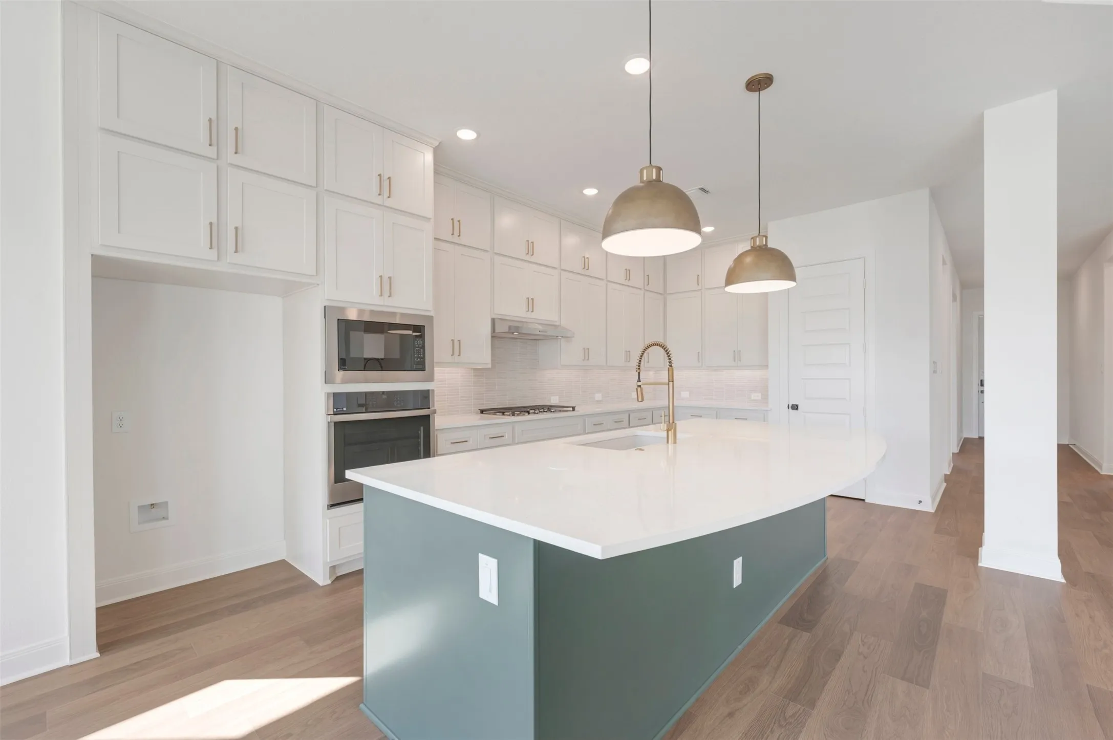Kitchen featuring floor-to-ceiling white cabinetry, a center island with a solid-surface countertop, wood-finish flooring, built-in stainless steel appliances, and dual dome pendant lighting