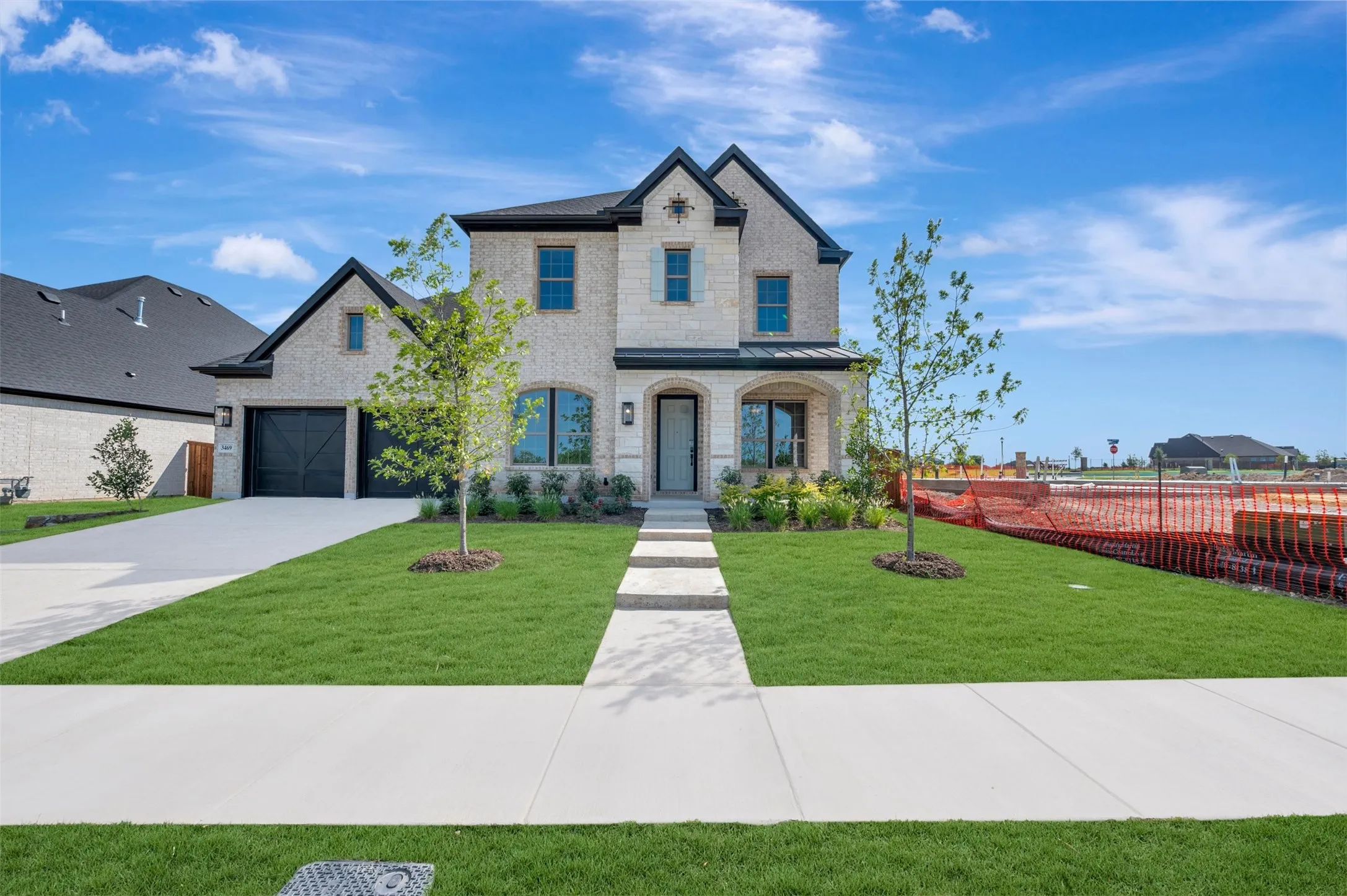 Two-story brick exterior featuring a multi-gabled roofline, dark-framed multi-pane windows, a recessed covered entryway, and an attached two-car garage with carriage-style doors