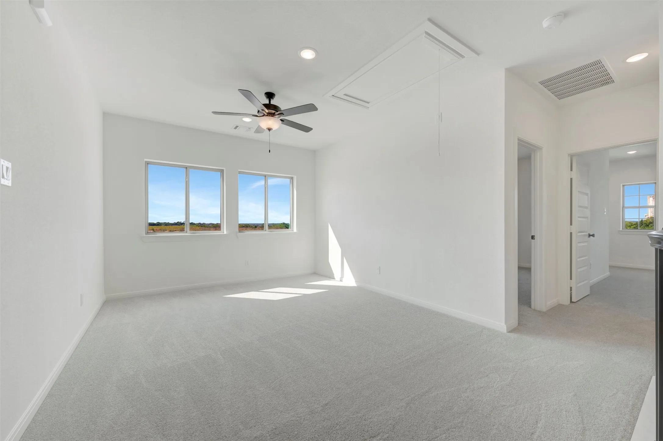 Room featuring neutral carpeting, recessed lighting, dual windows, and a ceiling fan with integrated light fixture