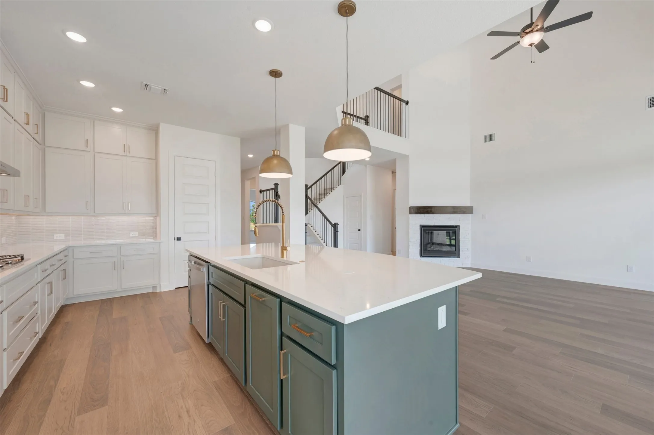 Kitchen featuring a center island with a stone-finish countertop and brass-tone hardware, shaker-style cabinetry, recessed lighting, dual pendant lights, and wood-finish flooring