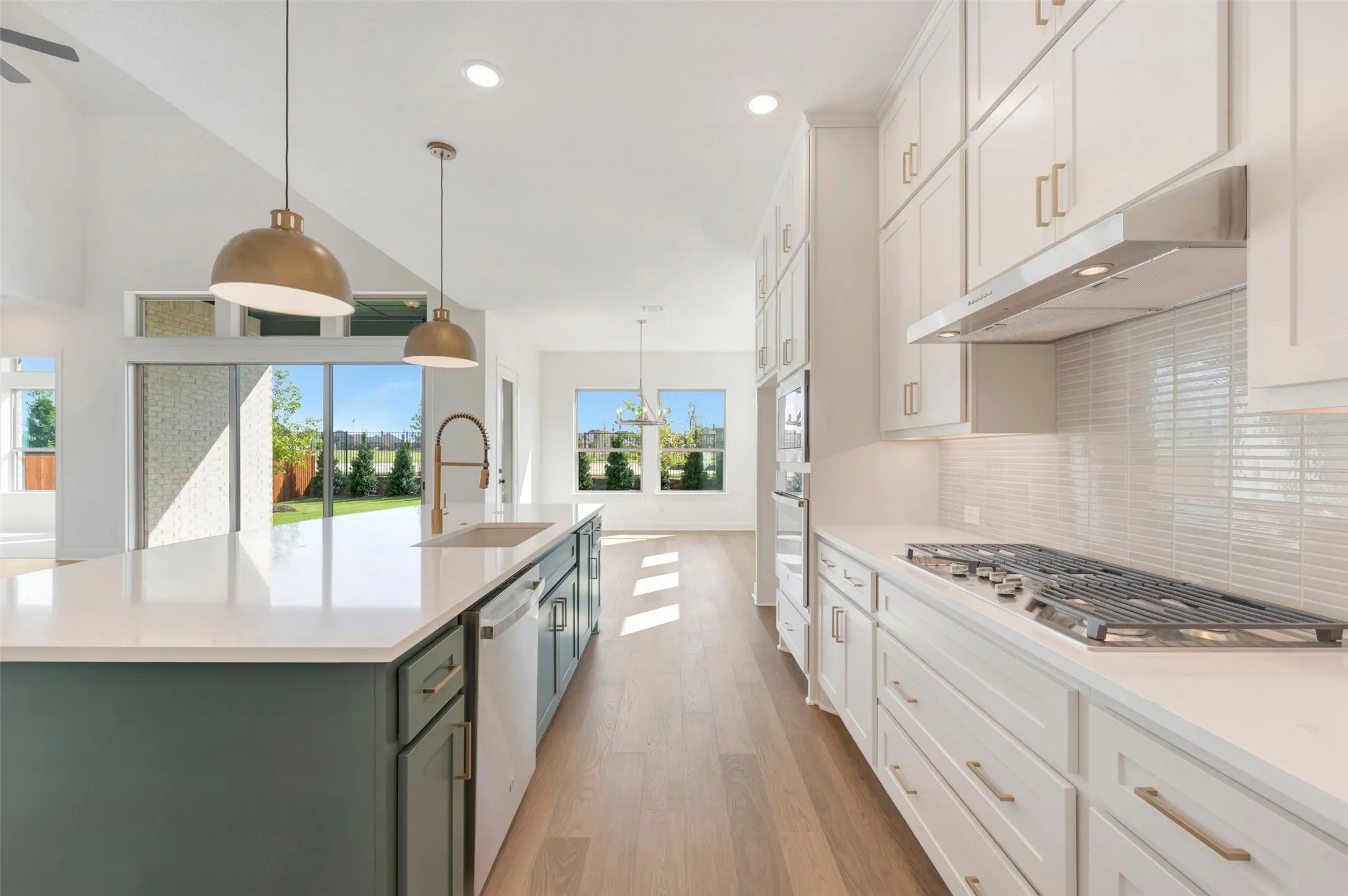 Kitchen featuring floor-to-ceiling cabinetry, a central island with a contrasting base, solid-surface countertops, horizontal tile backsplash, and wood-finish flooring