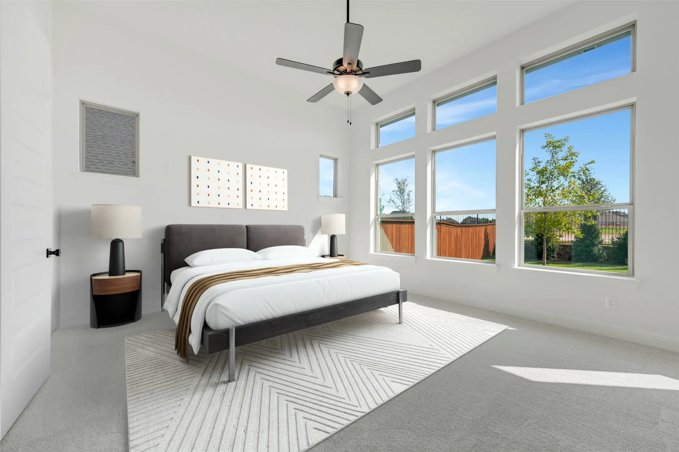 High ceilings featuring expansive windows with transom glass, neutral carpeting, and a multi-blade ceiling fan with integrated light fixture