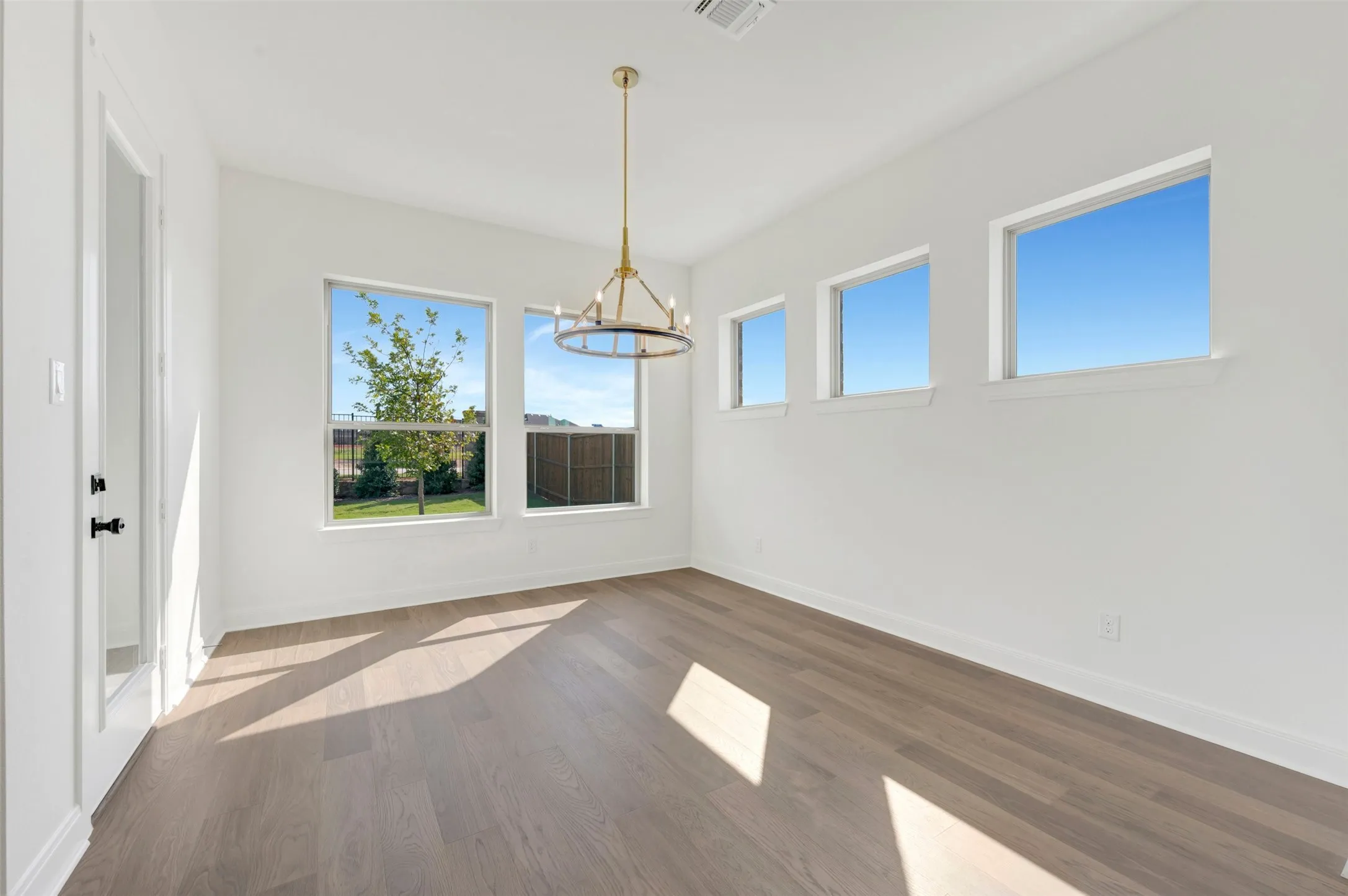 Wood-finish flooring, multi-pane windows, and a metal chandelier fixture