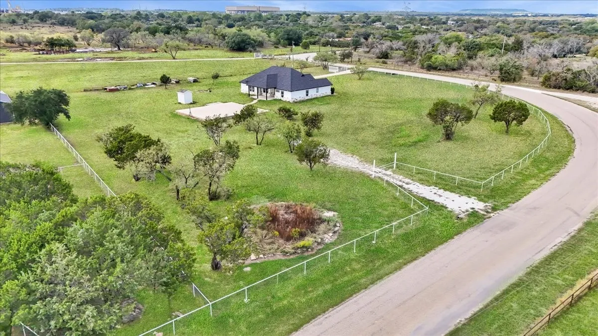 Expansive lot featuring mature trees, a perimeter wire fence, a dedicated gravel driveway, and a detached outbuilding