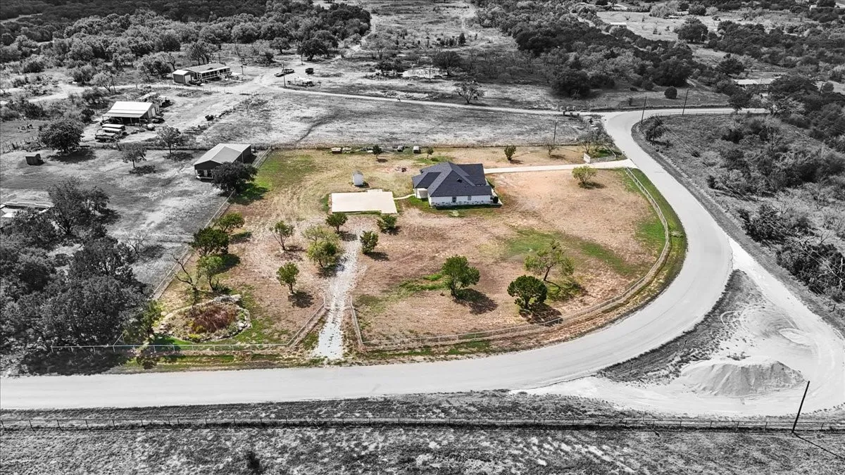 Expansive acreage featuring a paved road frontage, mature trees, a concrete parking pad, and a fenced perimeter
