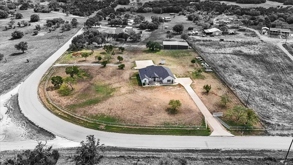 Corner lot featuring a multi-gabled roof, expansive acreage, paved driveway, and detached storage structure