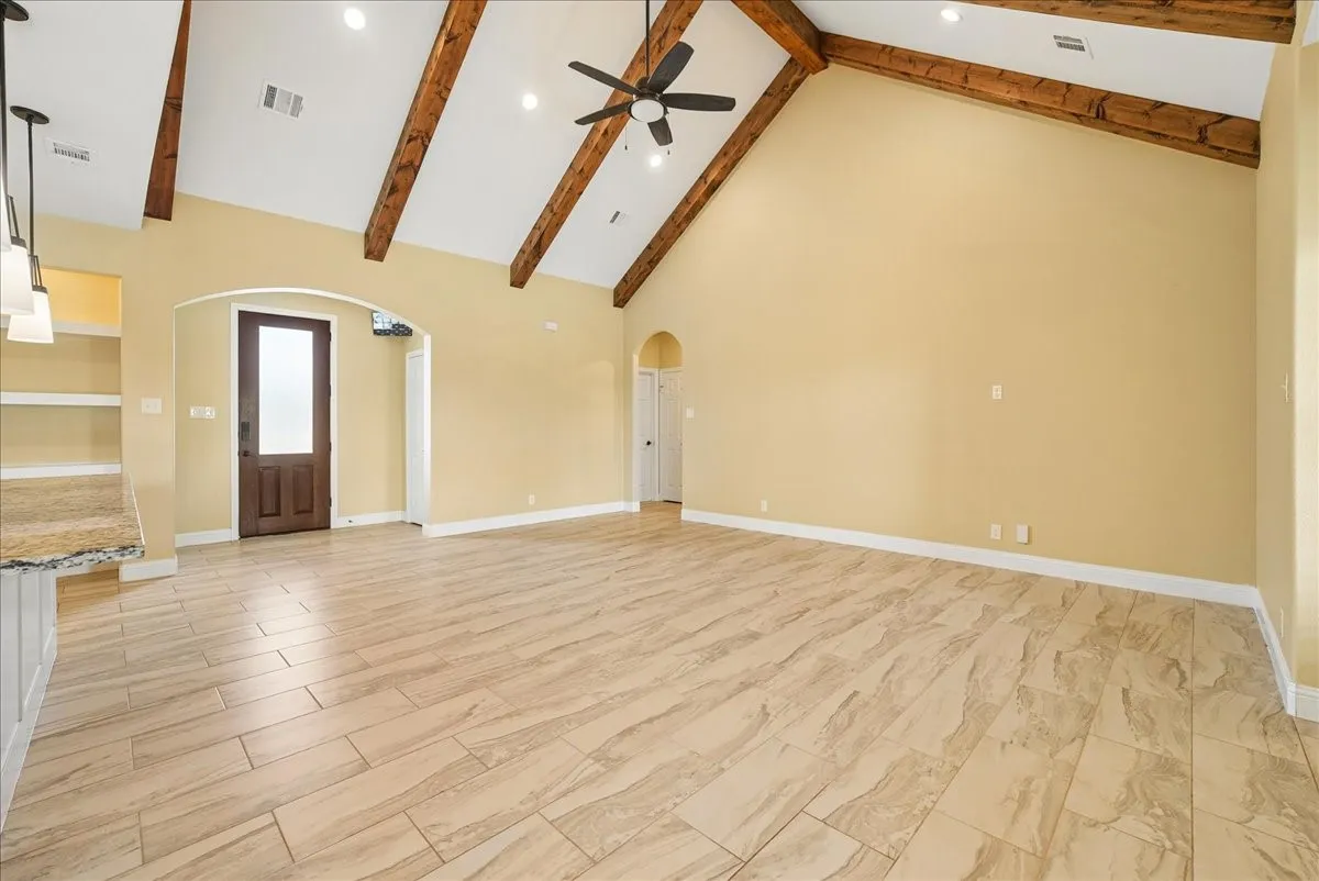Vaulted ceiling featuring exposed wood beams, tile flooring, arched doorways, recessed lighting, and a ceiling fan with integrated lighting