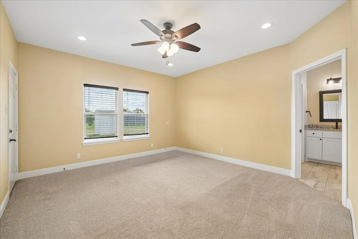 Neutral-toned interior room featuring carpeted flooring, a ceiling fan with integrated lighting, recessed lighting, and double-paned windows