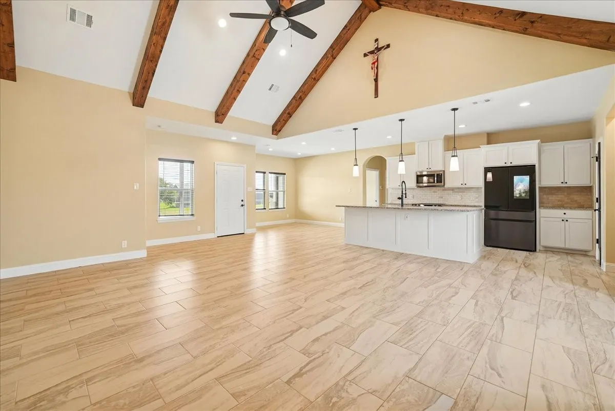 Vaulted ceilings featuring exposed wooden beams, tile flooring, recessed lighting, and a kitchen island with pendant lighting