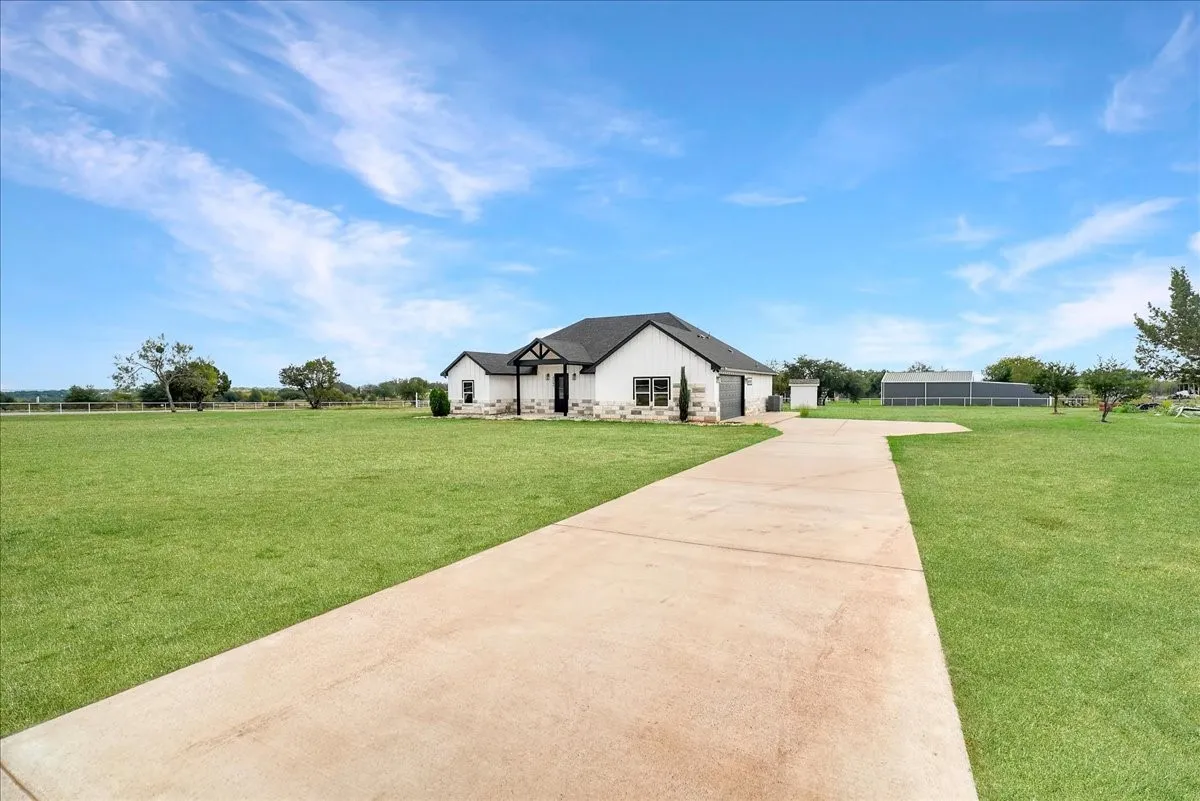 Single-story residence featuring stone and siding exterior, multi-gabled roofline, concrete driveway, and expansive lawn