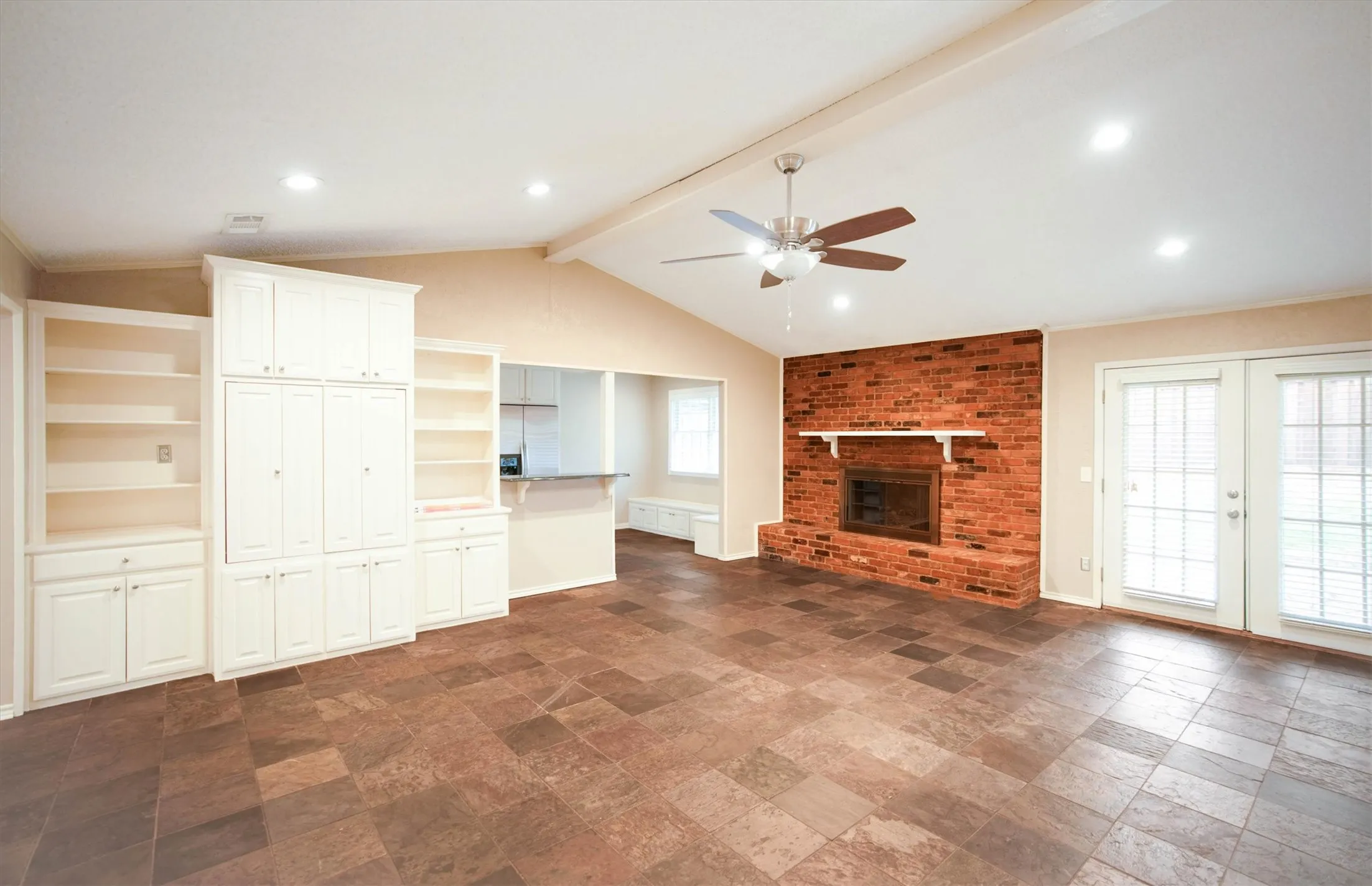 Spacious second living room with ceiling fan, fireplace, and built-ins
