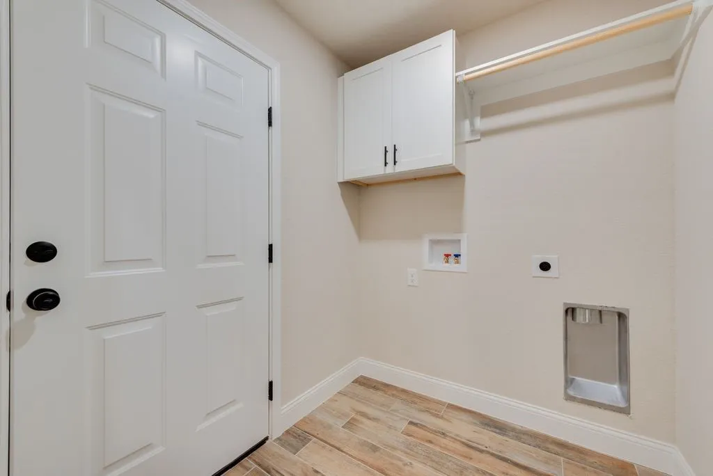 Utility area featuring wood-finish flooring, white shaker-style wall cabinetry with matte black hardware, and an integrated clothes rod
