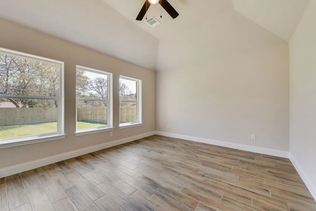 Vaulted ceilings, wood-finish tile flooring, and three oversized windows providing natural light, finished with a ceiling-mounted light fixture