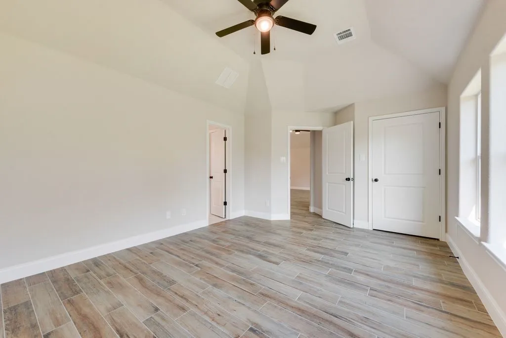 Vaulted ceilings, wood-finish tile flooring, ceiling fan, and multi-panel interior doors