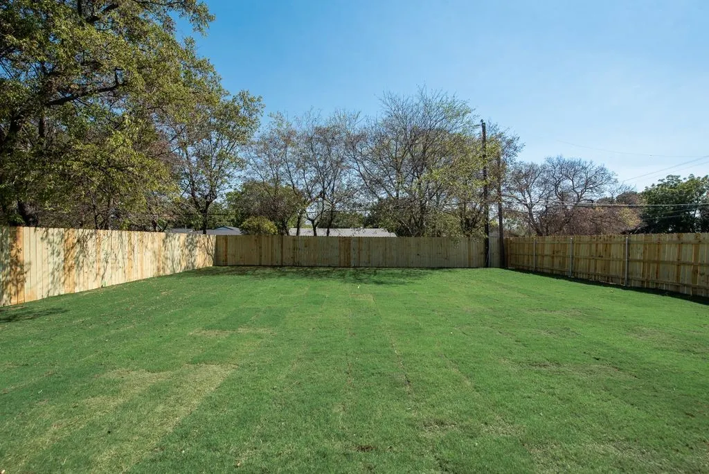Expansive backyard featuring a level lawn, full-perimeter wood fencing, and mature trees