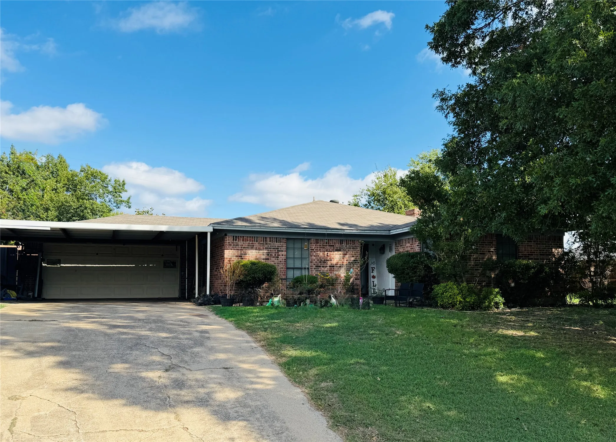 Single-story brick exterior featuring an attached carport and a paved driveway