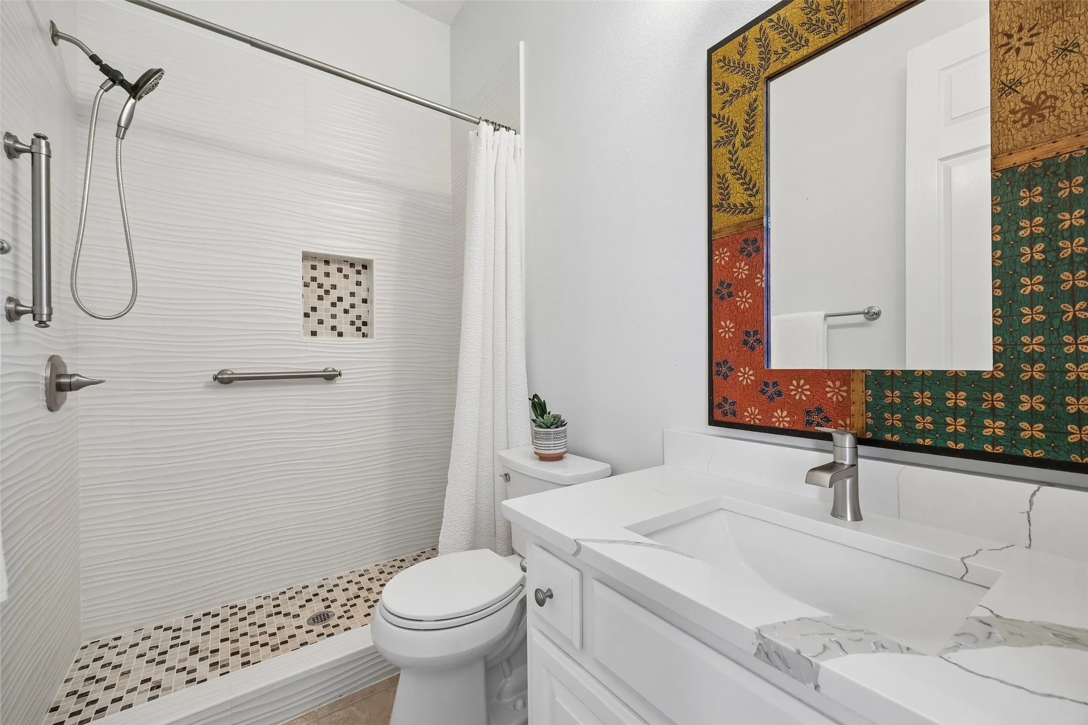 Updated downstairs guest bath featuring a spacious walk-in shower, quartz countertop, and stylish finishes, conveniently serving the private guest
suite.