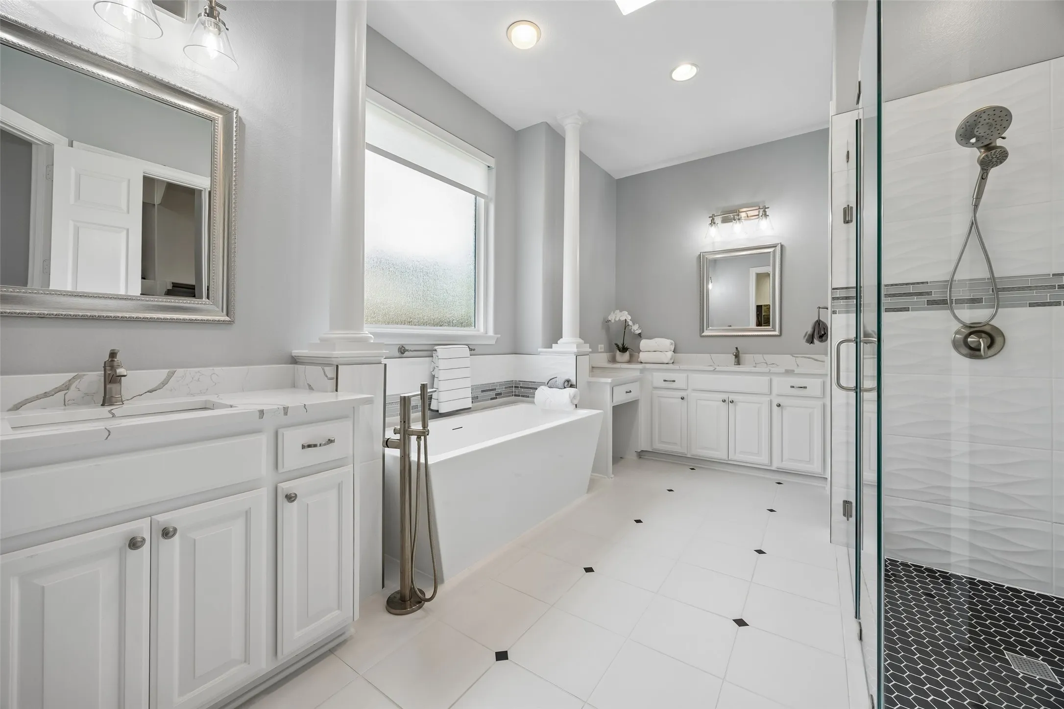 Spa-inspired primary bath featuring a freestanding
soaking tub, oversized walk-in shower, dual
vanities, and dual closets, including one with access to the utility room for everyday
convenience.
