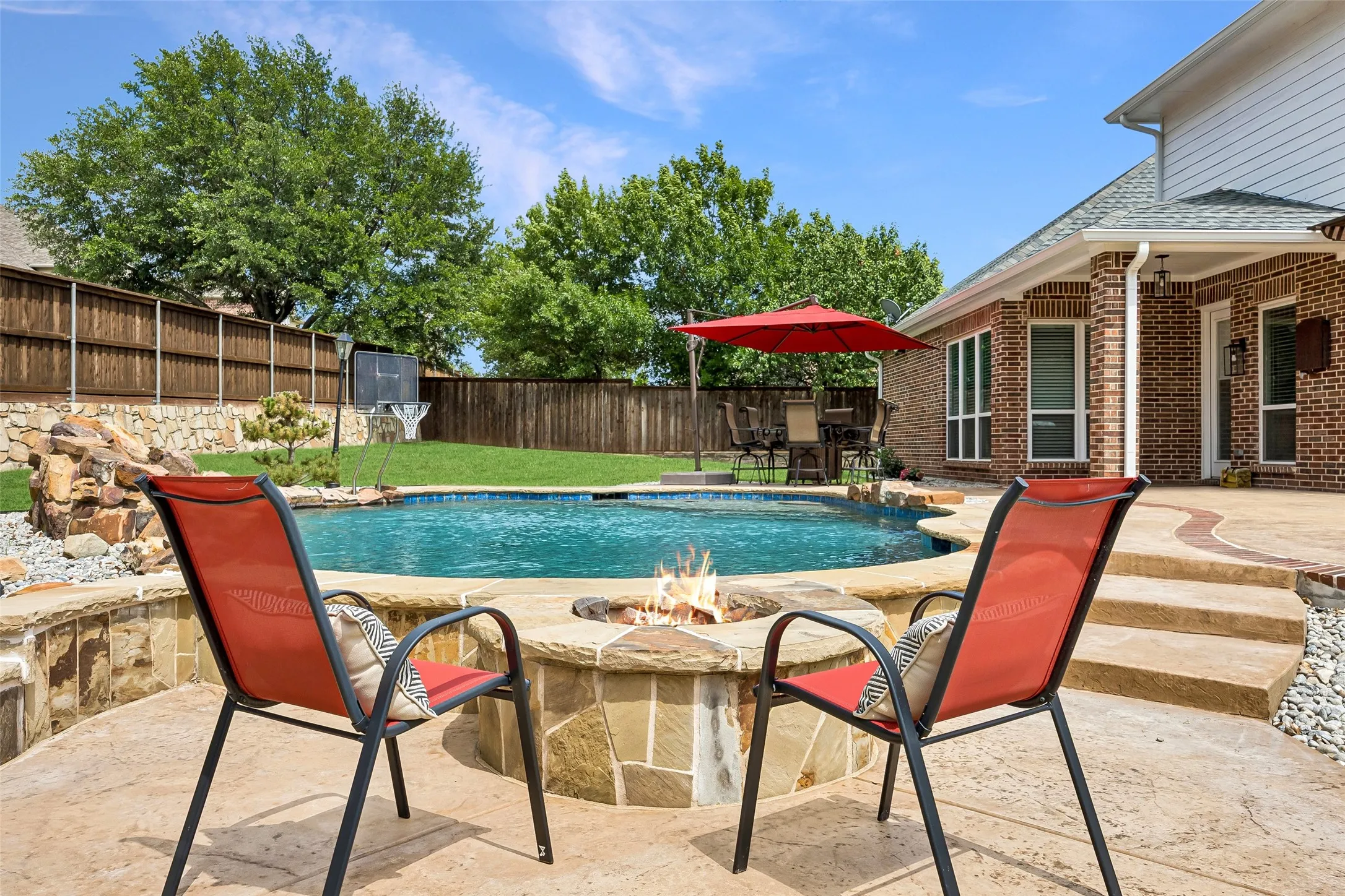 Resort-style backyard oasis featuring a sparkling
pool, fire pit seating area, expansive patio, and generous green space for entertaining and play.