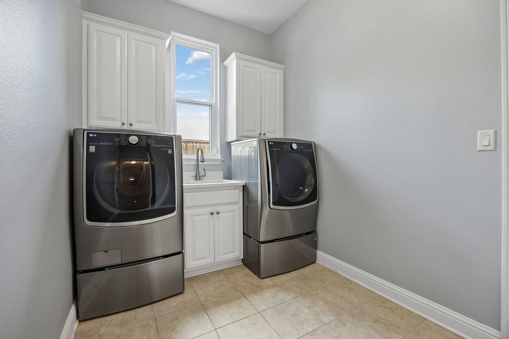 Spacious utility room with sink, upper cabinetry, and flexible gas or electric dryer connections for
added convenience.