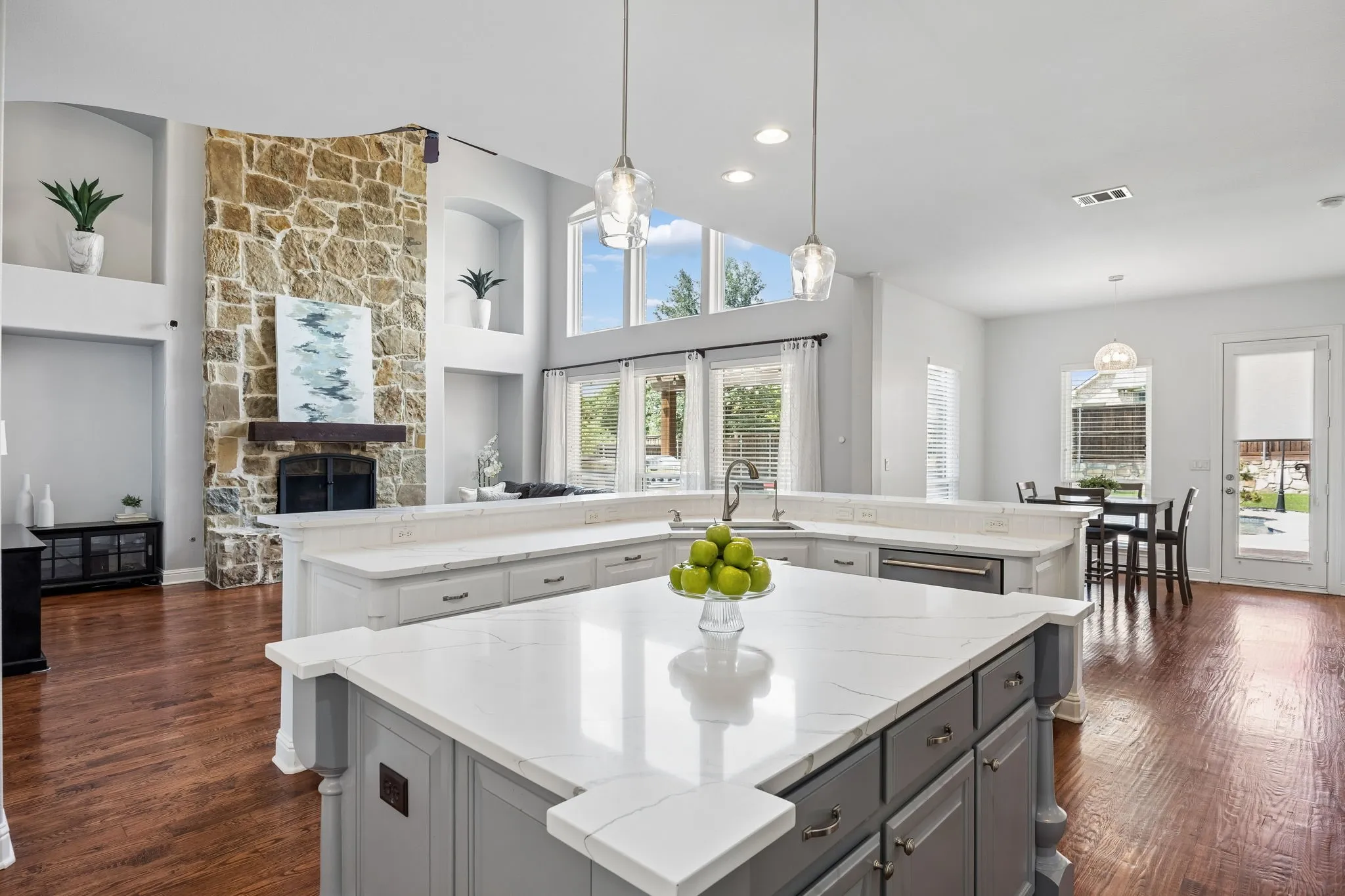 Stunning open-concept kitchen with expansive
island, quartz countertops, and seamless connection to the light-filled living spaces, highlighted by soaring ceilings and a dramatic stone fireplace.