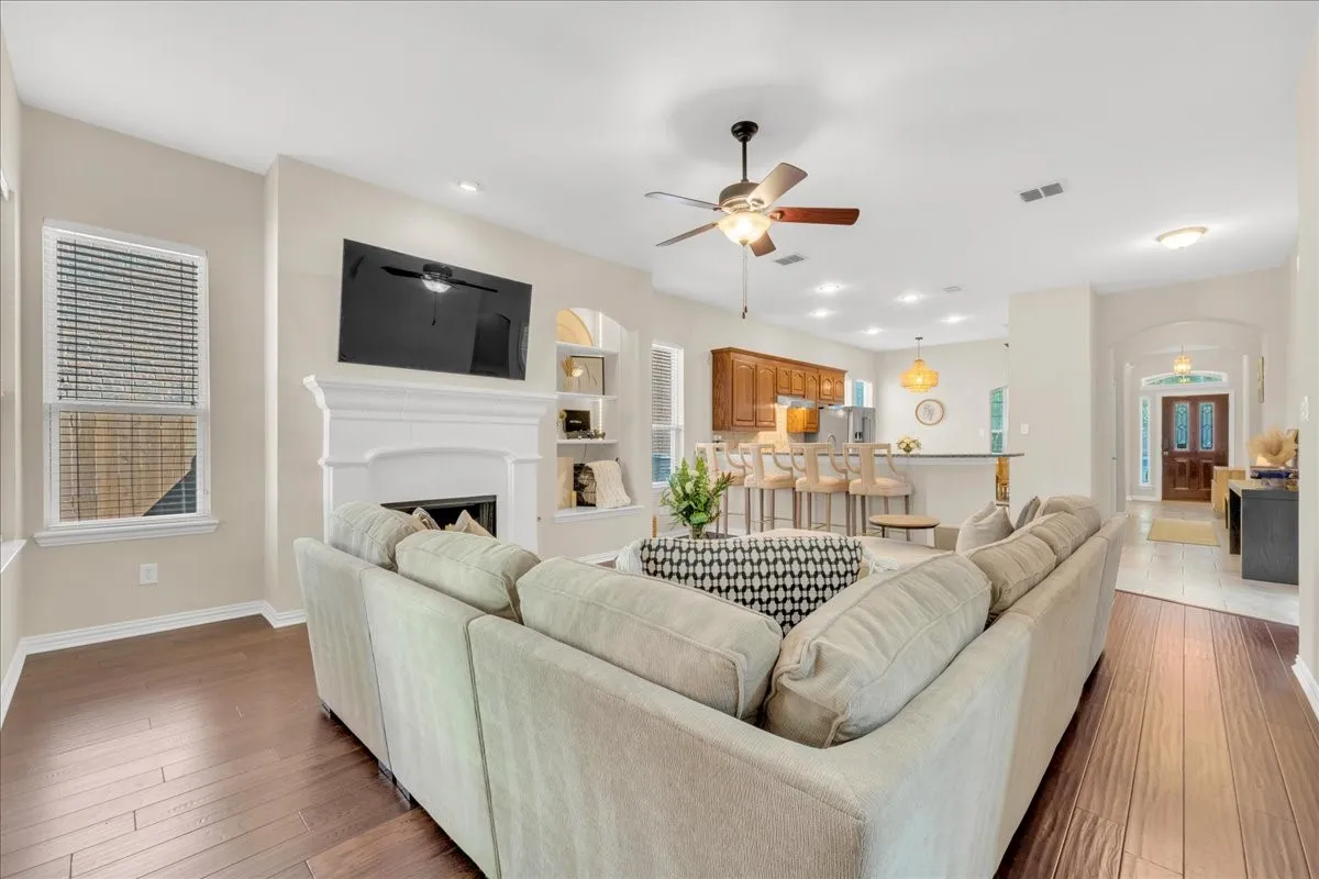 Wood-finish flooring throughout, with a classic white mantel fireplace and built-in shelving