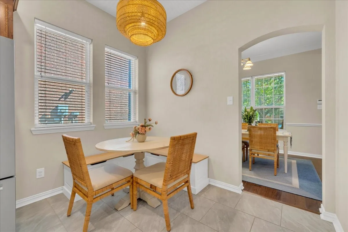 Light-filled dining area featuring two windows with blinds, a built-in bench, and tile flooring