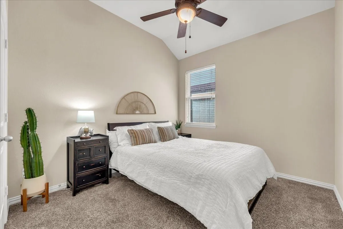 Vaulted ceiling, ceiling fan, window with blinds, and carpeted flooring