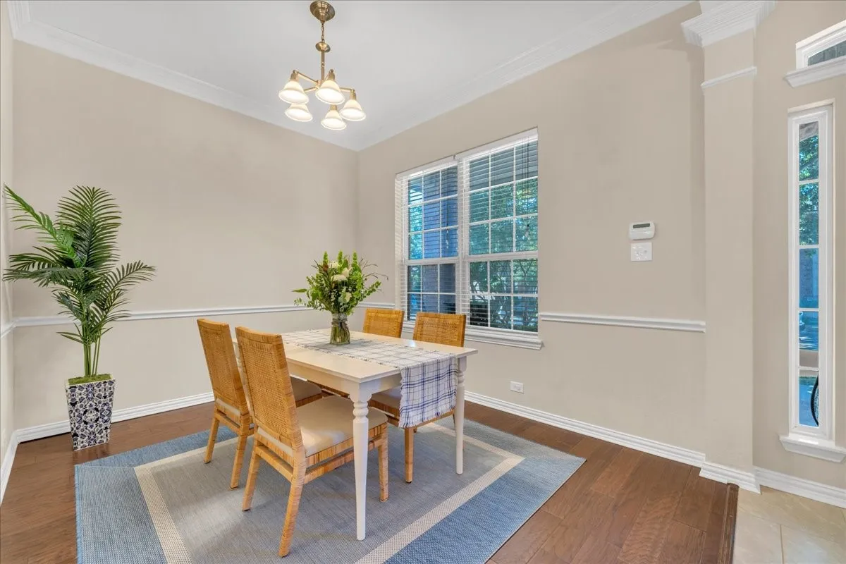 Wood-finish flooring, crown molding, chair rail molding, and a multi-pane window with blinds